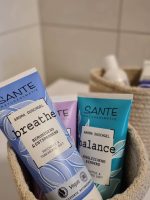Nahaufnahme von Sante Naturkosmetik Duschgel-Tuben mit den Aufschriften breathe und balance in einem kleinen geflochtenen Körbchen.