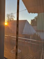 Blick durchs Moskitonetz auf den Balkon in den Sonnenuntergang im Schlafzimmer 2 der Perle am Kobernaußerwald
