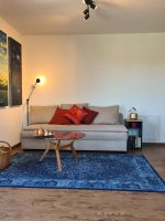 Blick ins Wohnzimmer der Perle am Kobernaußerwald mit Sofa und kunstvoll gestalteter Dekowand