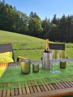 Gedeckter Gartentisch mit Sektkühler und Gläsern mit Blick auf den Wald