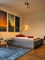 Gemütliches Zimmer mit gemütlichem Schlafcouch-Bett, blauem Teppich und stimmungsvoller Beleuchtung