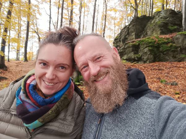 Die Gastgeber der Ferienwohnung Perle am Kobernaußerwald - Anna und Florian - lächelnd im herbstlichen Wald